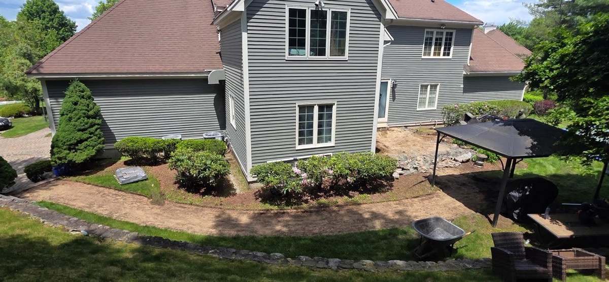 Backyard planting beds shaped and prepped around a large house