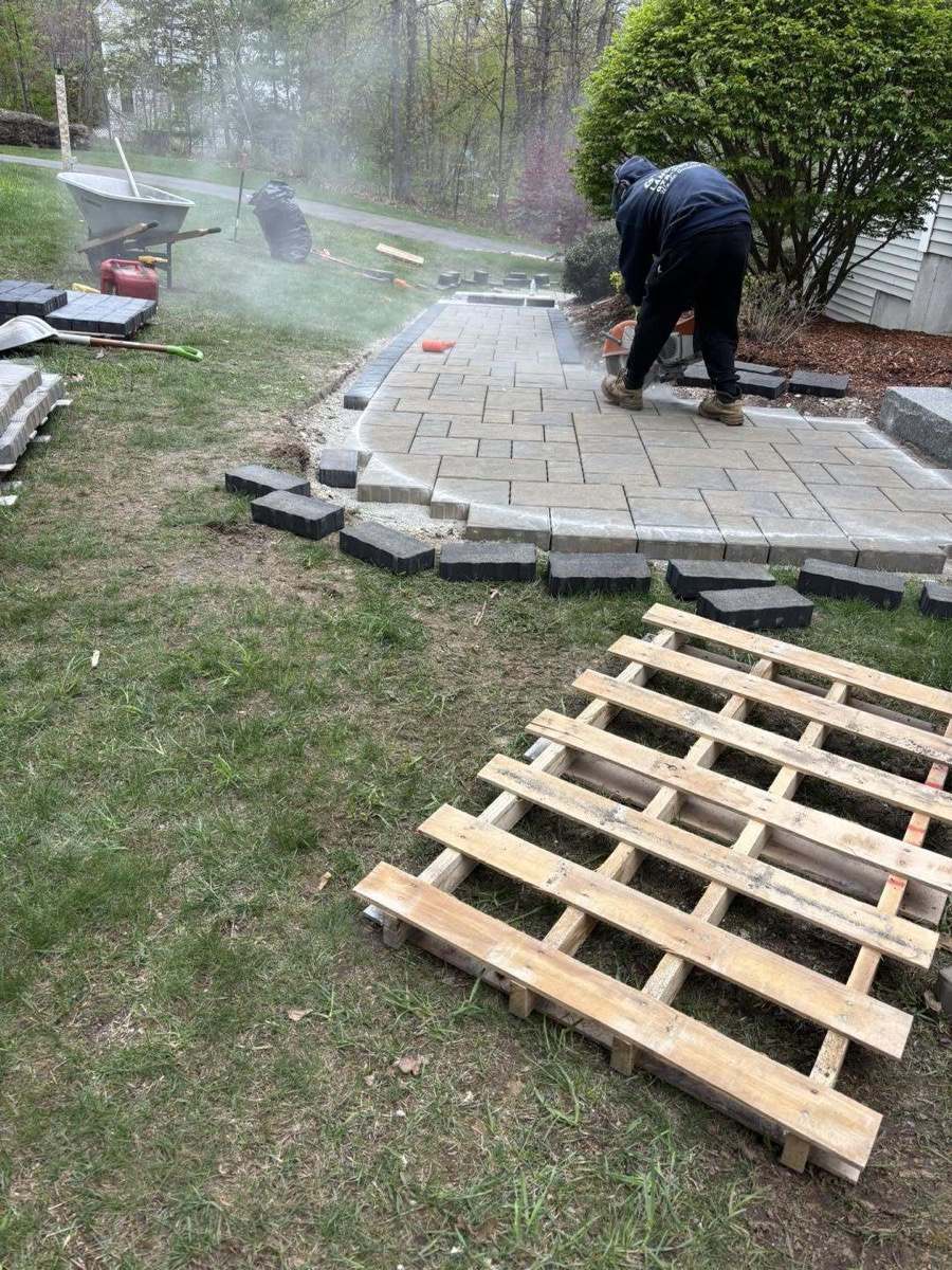 Gomez crew member cutting and laying pavers on a backyard patio
