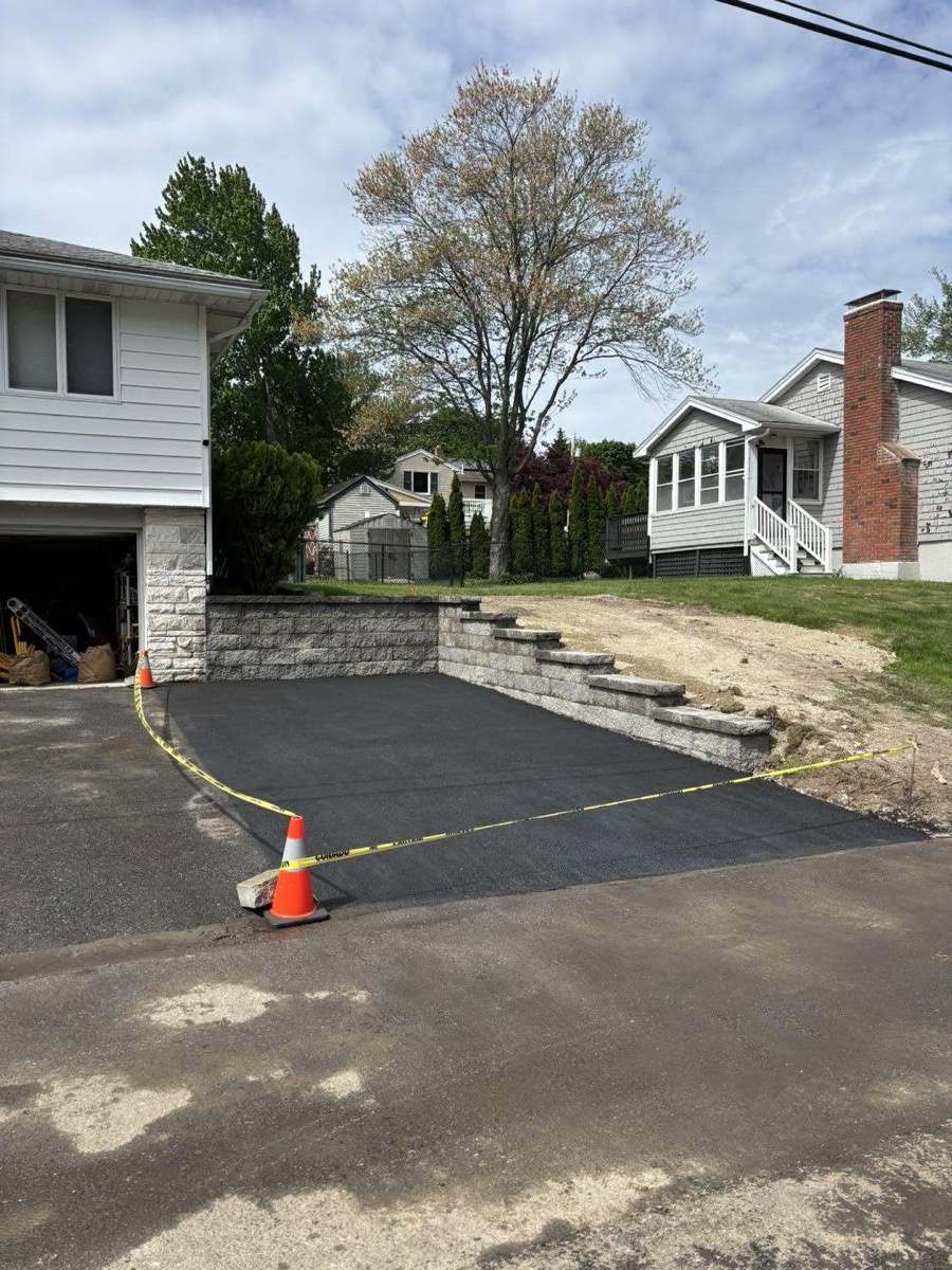 Fresh asphalt driveway with new block retaining wall and steps